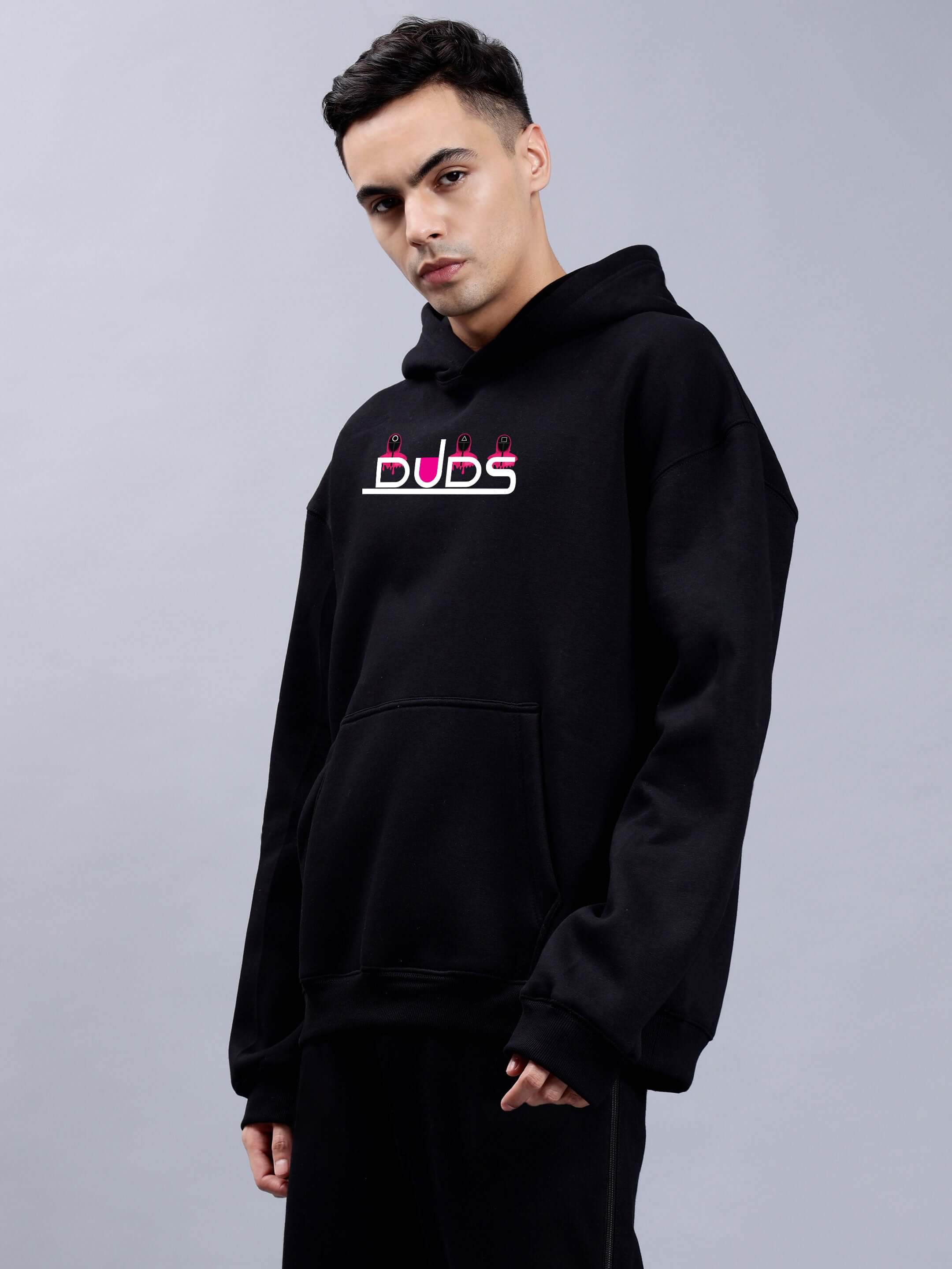 Model wearing Squid Game Oversized Hoodie Men Black with bold lettering, showcasing streetwear style from the popular series.