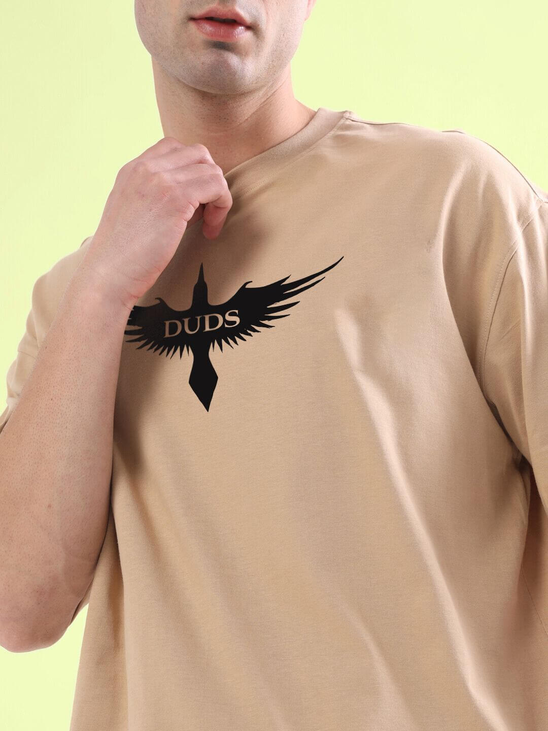 SILENT BUT POWERFUL PRINTED T-SHIRT BEIGE with black eagle logo on front, worn by a model against a light green background.