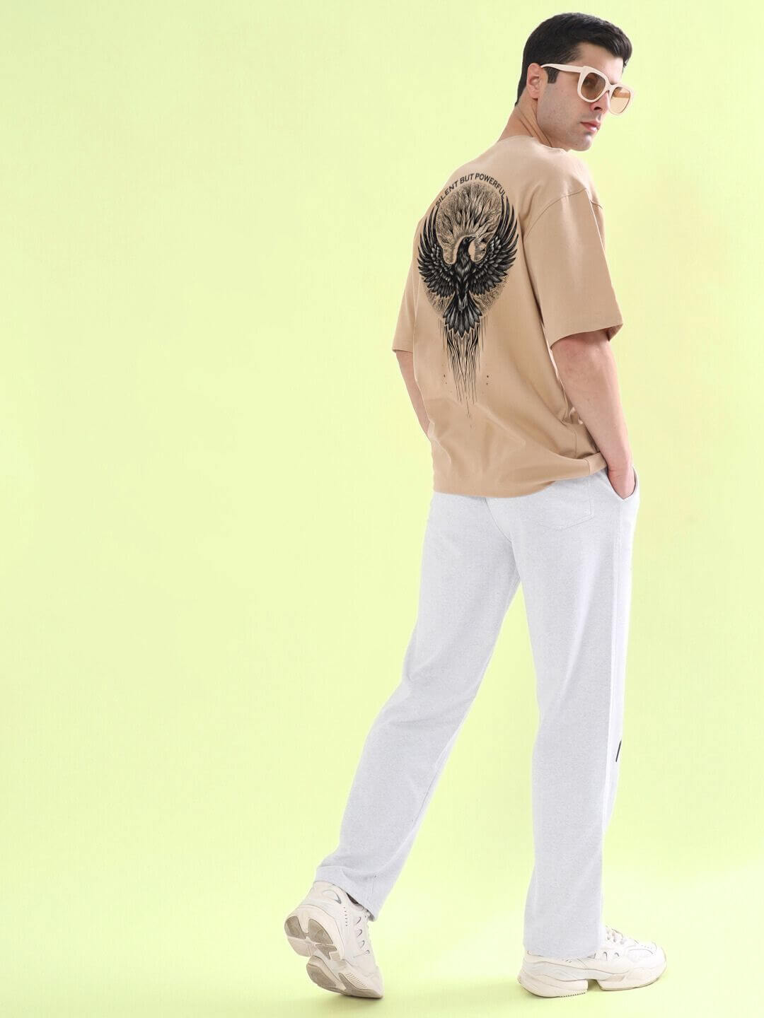 SILENT BUT POWERFUL PRINTED T-SHIRT BEIGE with bold design on the back, worn by a model standing against a light green background.