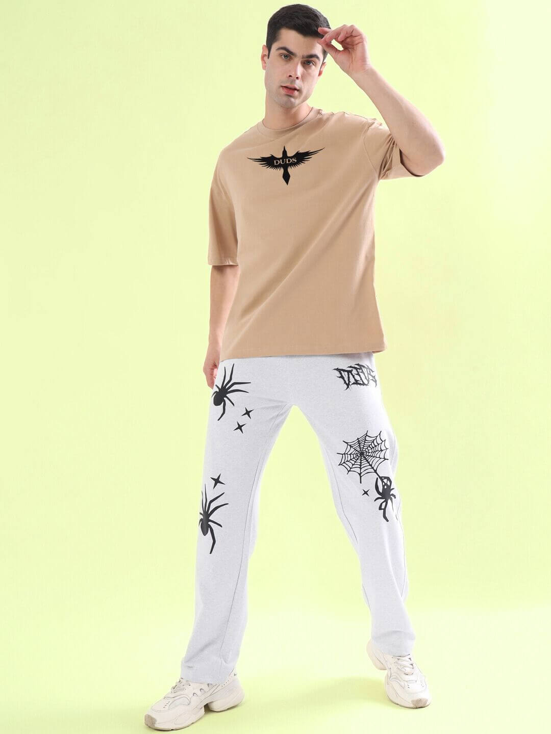 Man wearing SILENT BUT POWERFUL PRINTED T-SHIRT BEIGE in a stylish pose against a light green background.