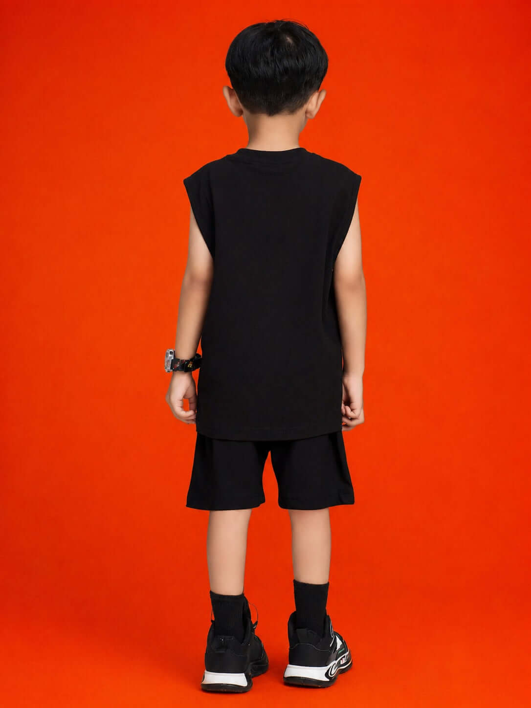QUACK ATTACK GRAPHIC SHORTS FOR BOYS GIRLS BLACK worn by a child from the back against an orange background.