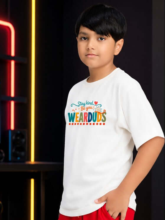 STAY KIND GRAPHIC T-SHIRT FOR BOYS GIRLS WHITE RED worn by a boy, featuring colorful Stay Kind design in white shirt.