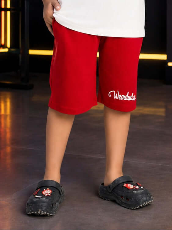 STAY KIND GRAPHIC SHORTS FOR BOYS GIRLS WHITE RED displayed on a child wearing red shorts and casual footwear.