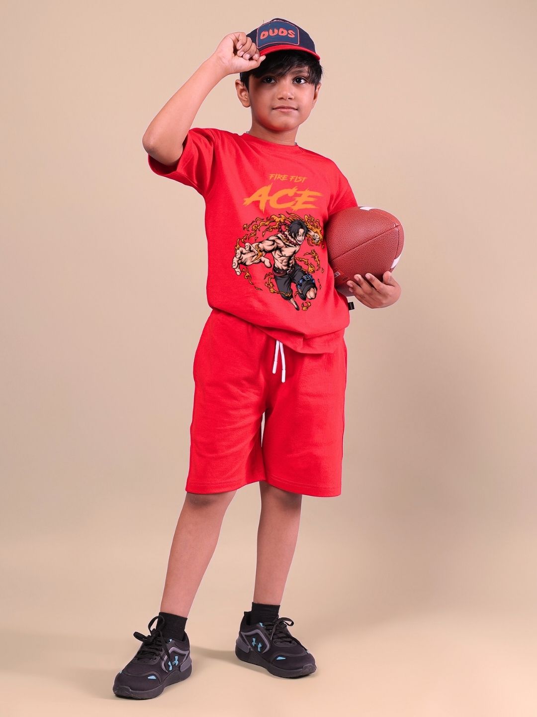 Child wearing ACE red co-ord set for boys and girls, holding a football, showcasing vibrant style and comfort.