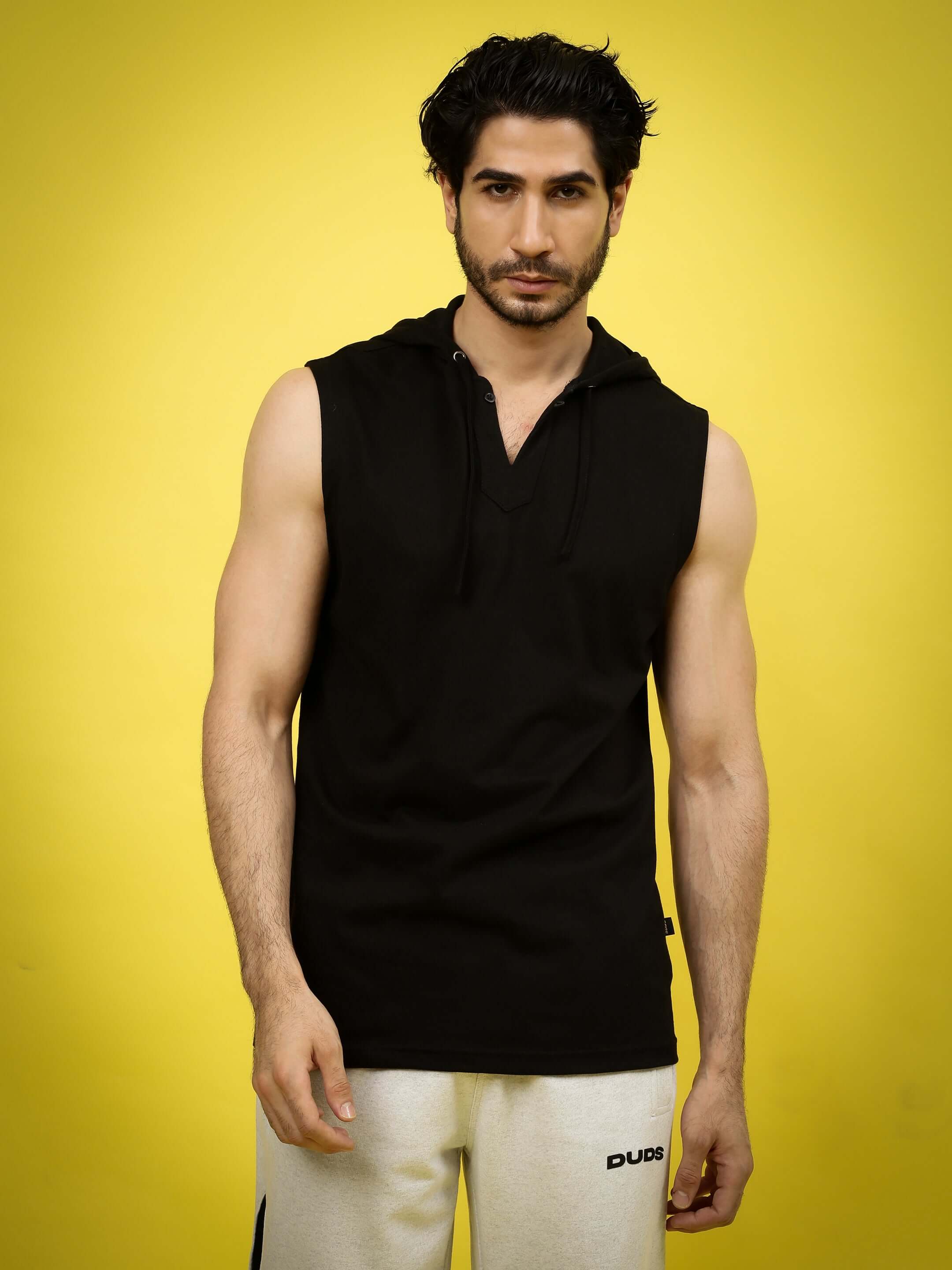 Model wearing ACME over-sized hood t-shirt in black, highlighting custom fit option with DUDS brand, set against a yellow background.