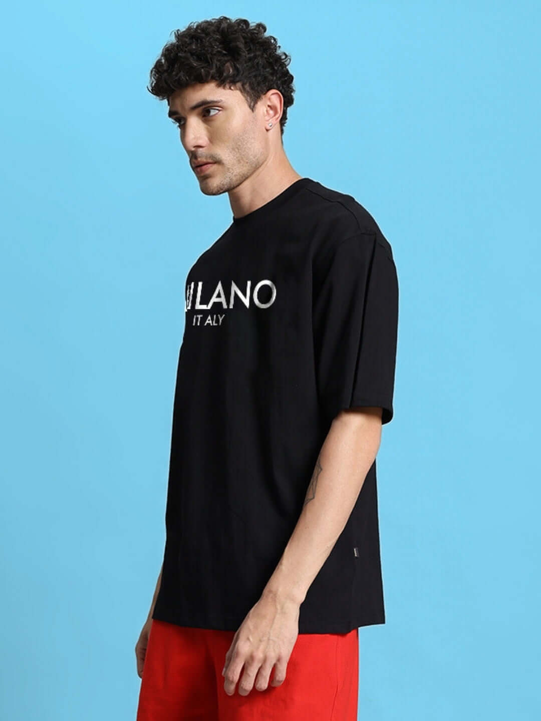 Model wearing black oversized t-shirt with white text, against blue background, showcasing premium cotton fabric and modern fit.