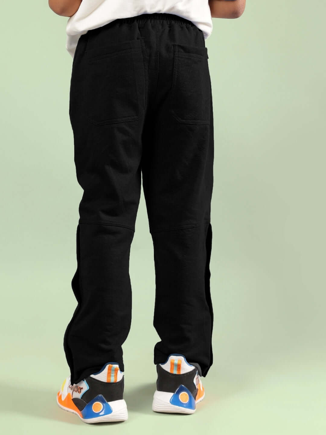 ADONIS CO-ORD FOR BOYS GIRLS OFF WHITE-BLACK stylish pants displayed from the back view on a model with trendsetting sneakers.