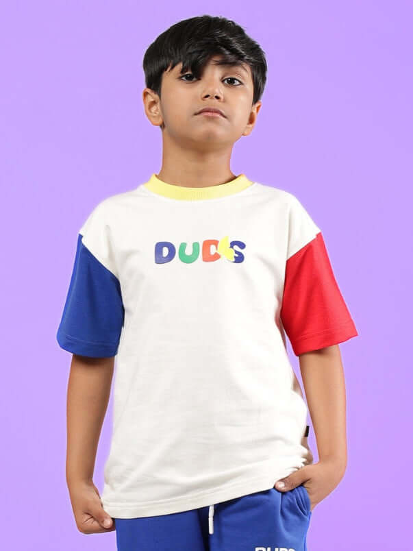 Child wearing ADONIS oversized off-white t-shirt with colorful sleeves by DUDS, perfect for boys and girls. Stylish casual wear.