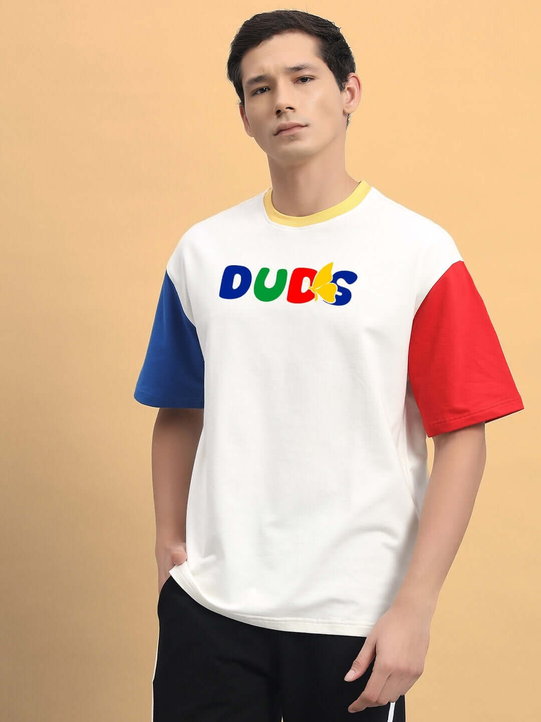 Man wearing an oversized white T-shirt with color blocked blue and red sleeves, featuring bold lettering on the front, suitable for casual wear.