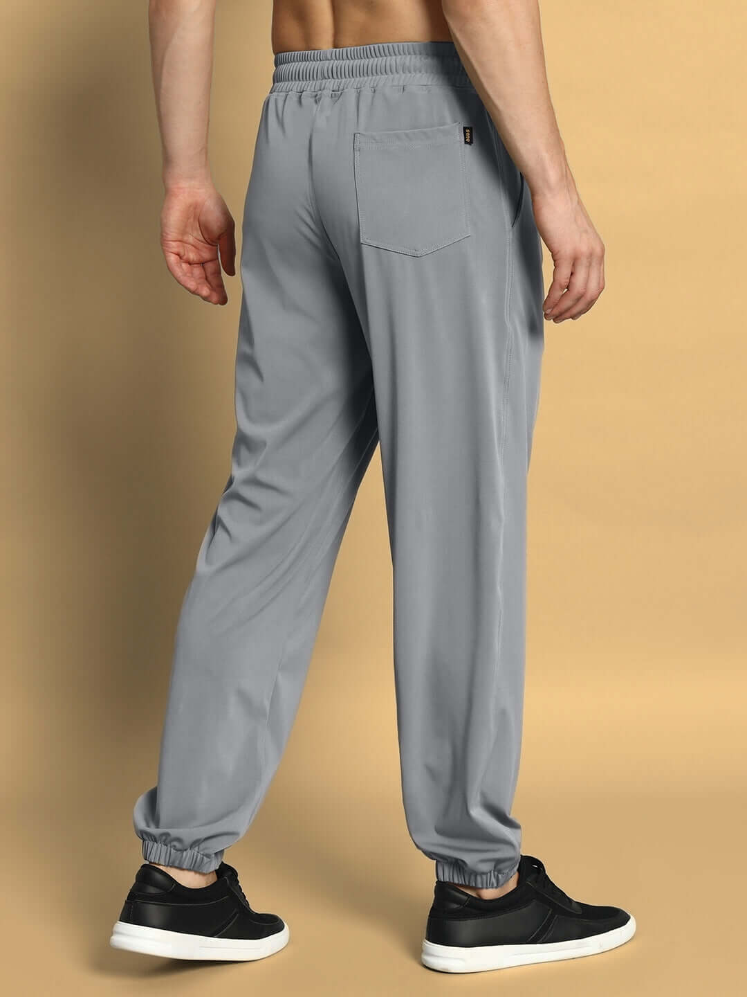 Back view of grey AGILE RELAXED PANT JOGGER by DUDS, featuring elastic waistband and cuffed ankles, worn with black sneakers.