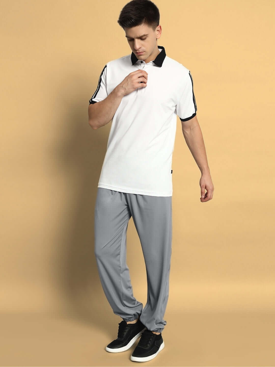 Man wearing grey Agile Relaxed Pant Jogger, paired with white and black polo shirt, showcasing casual style.