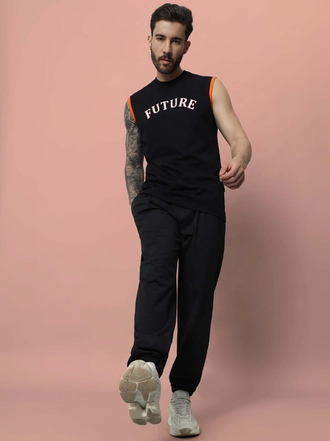 Man wearing AGILE RELAXED PANT JOGGER in black, casual style with a sleeveless top, standing against a pink background.