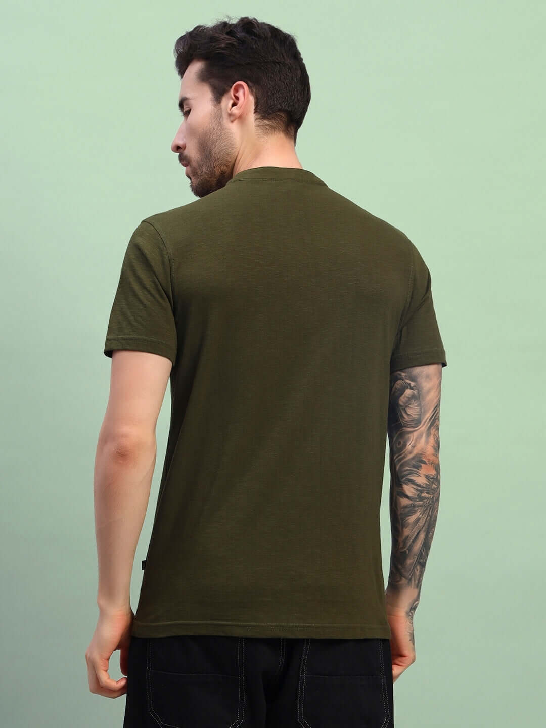 Back view of a man wearing an ALBET Regular Fit Olive Green T-Shirt, made from premium heavy cotton slub fabric, showcasing bio-washed texture.