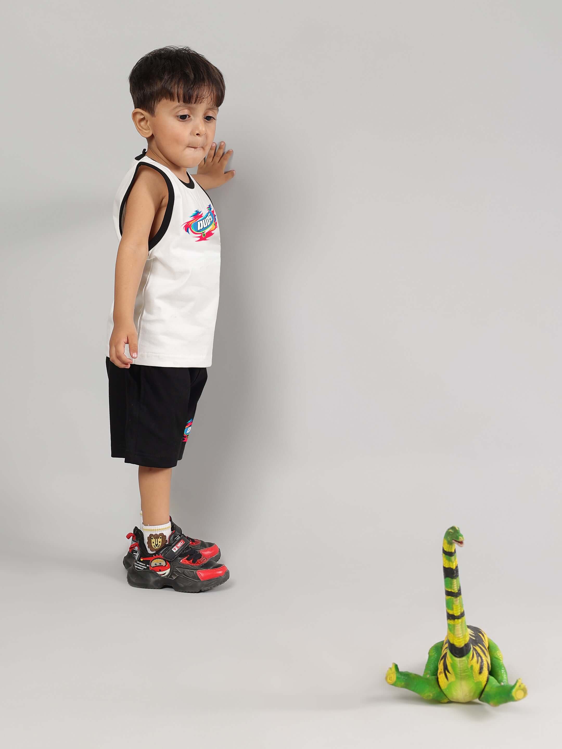 Child wearing ALIEN SUMMER CO-ORD FOR BOYS GIRLS OFF WHITE-BLACK set next to a toy dinosaur.