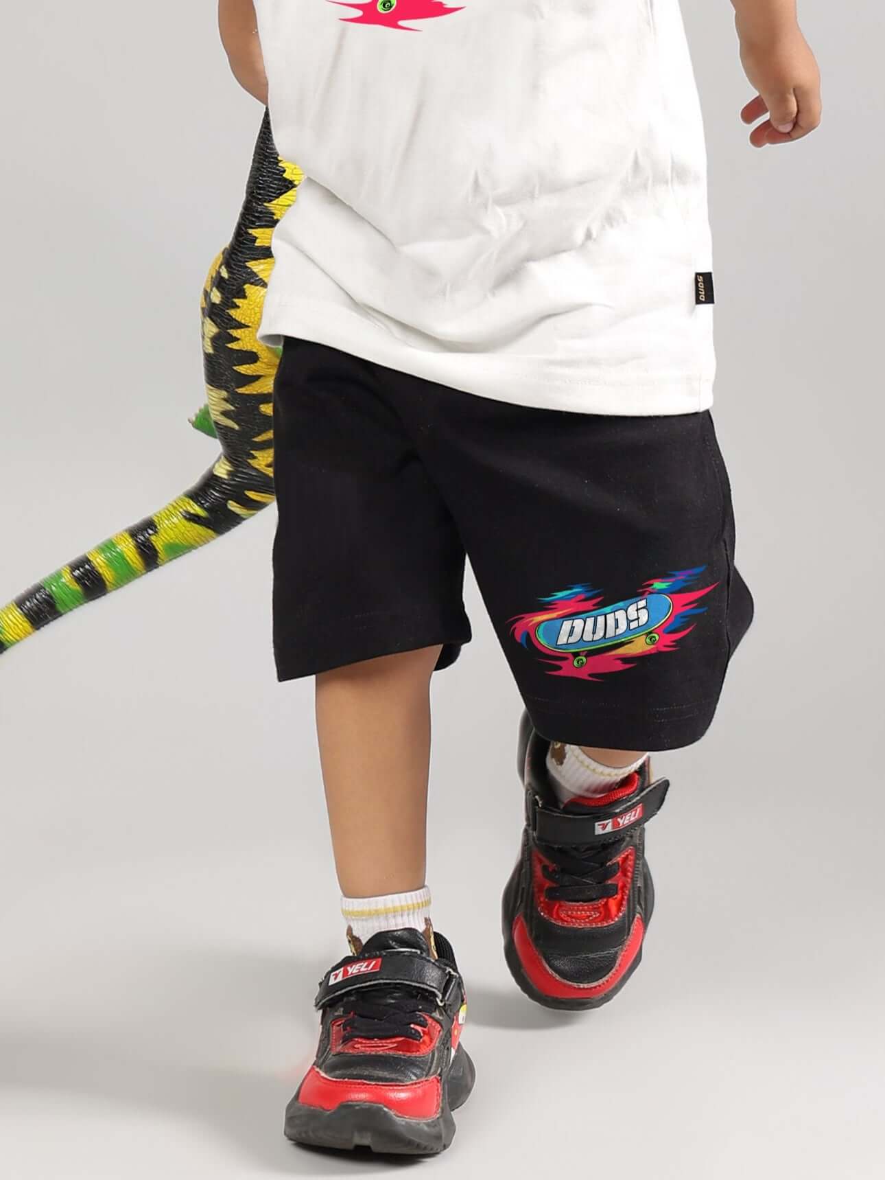 Child wearing black ALIEN shorts for boys and girls by DUDS, featuring colorful branding, customizable fit, and comfortable design.