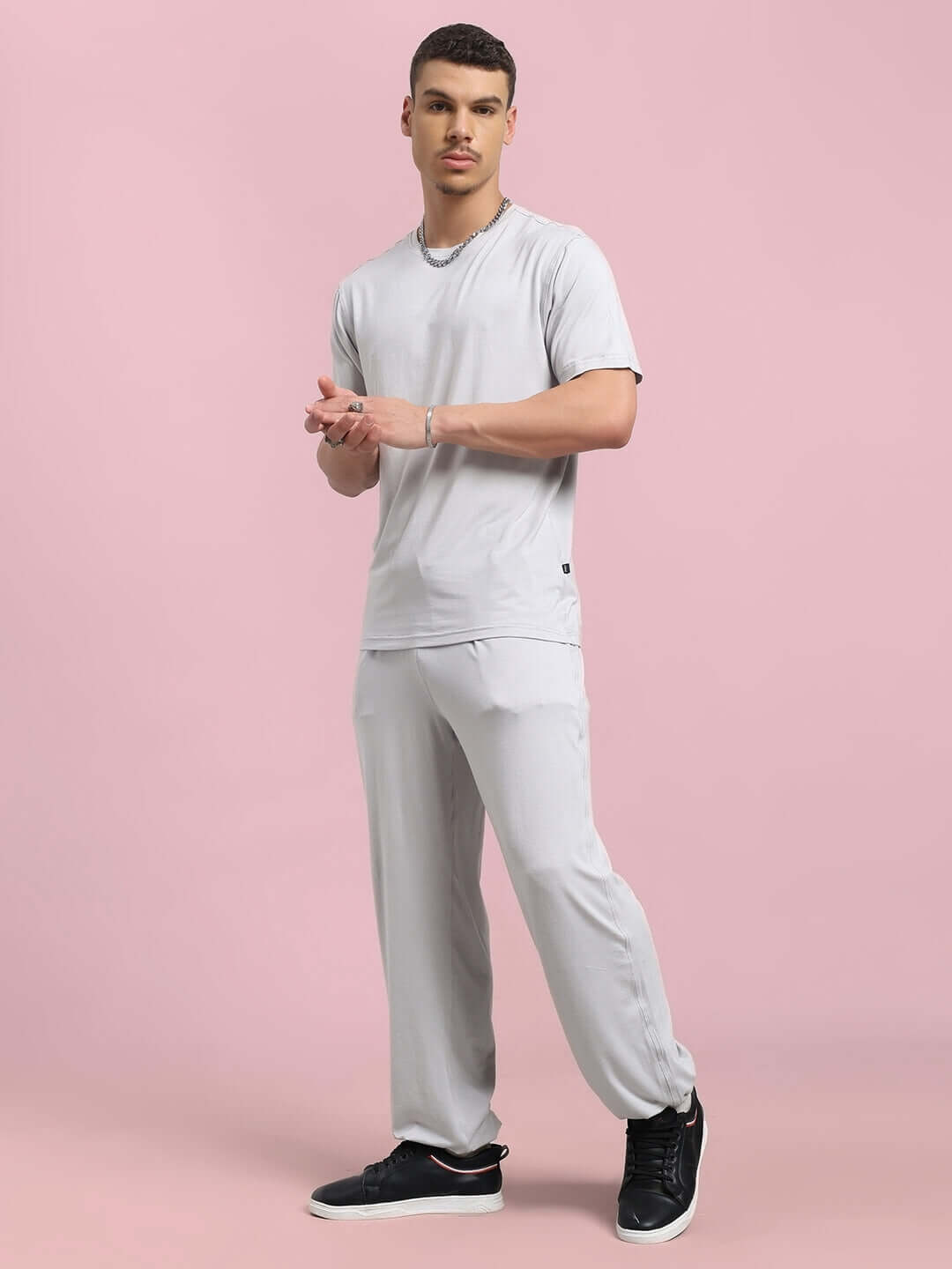 Man wearing grey AMBLE CO-ORD SET made of premium modal fabric, standing on pink background. Stylish and comfortable attire.