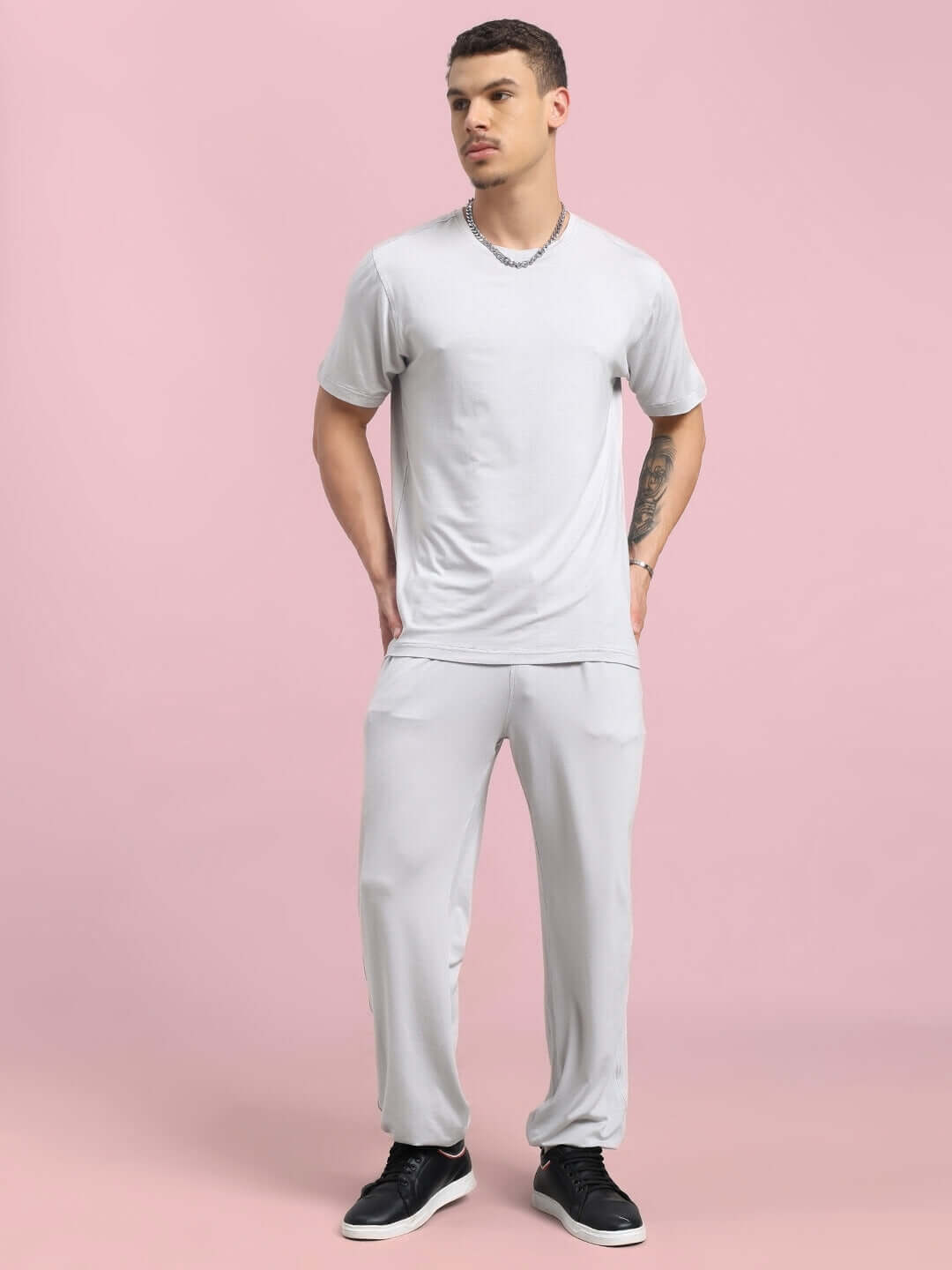 Man wearing AMBLE CO-ORD SET in grey, made from premium heavy gauge modal fabric, standing against a pink background.