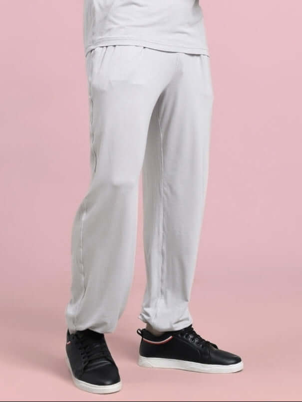 Person wearing grey Amble Relaxed Fit Joggers with black sneakers on a pink background.