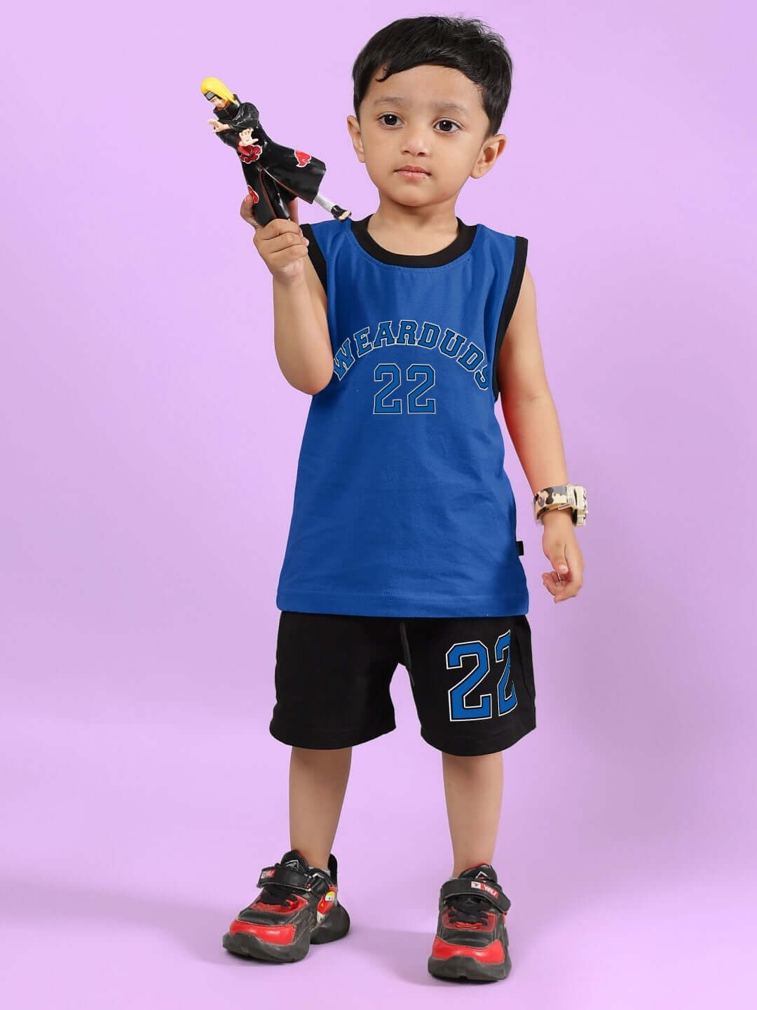 Child wearing AMIGA CO-ORD FOR BOYS & GIRLS BLUE BLACK, holding a toy against a purple background. Stylish and sporty outfit for kids.
