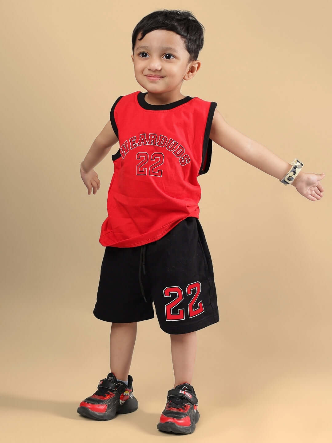 Young child in red and black AMIGA co-ord outfit, featuring sports-themed design, stands confidently, showcasing versatility for kids.