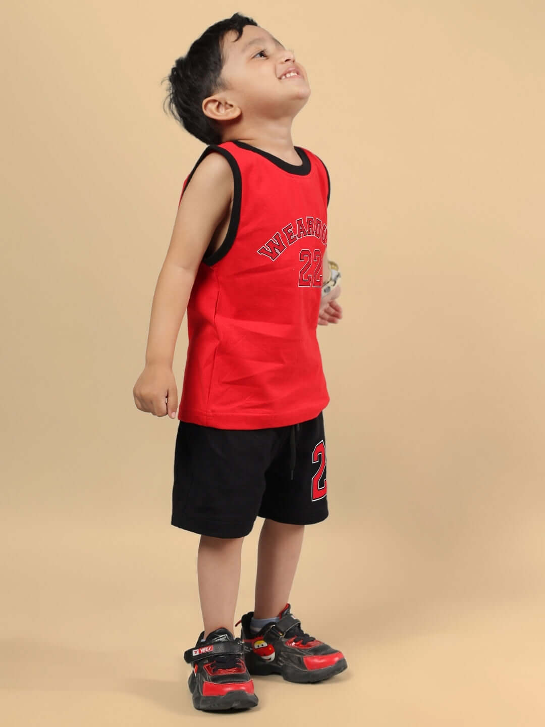 Boy wearing AMIGA CO-ORD FOR BOYS & GIRLS RED BLACK outfit, featuring red top and black shorts, standing on beige background.