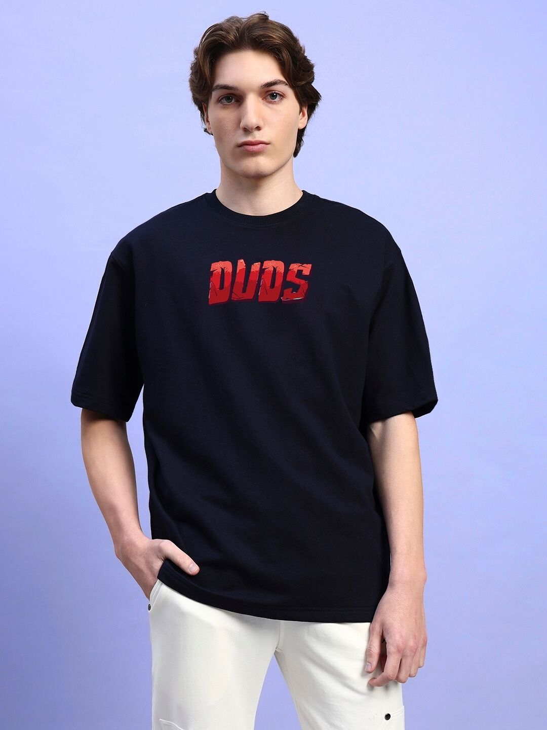 Person wearing AMPERES PRINT OVERSIZED T-SHIRT BLACK standing against light purple background.