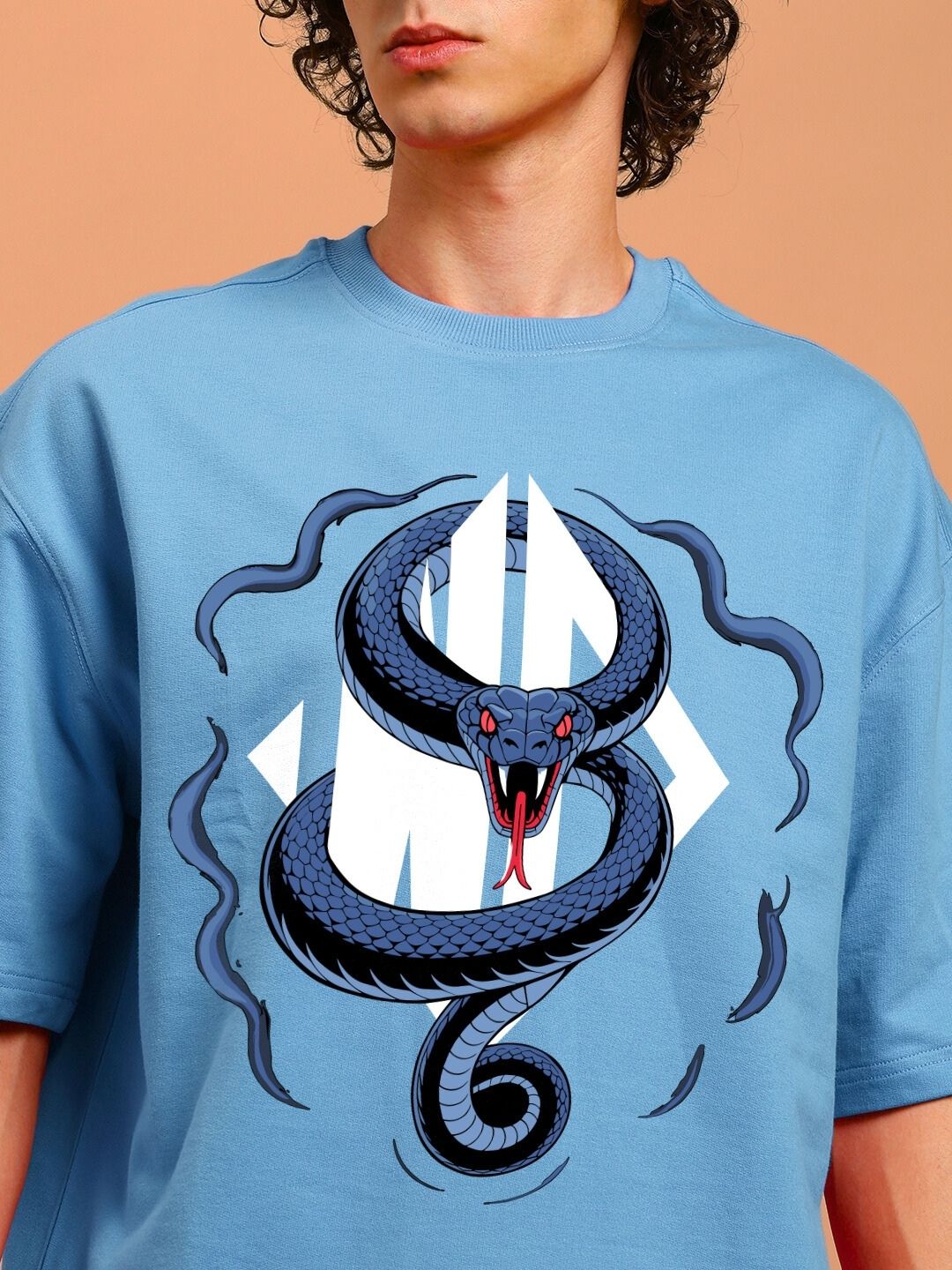Person wearing ANGRY SNAKE WD PRINTED OVERSIZED T-SHIRT LIGHT BLUE with bold snake design on front.