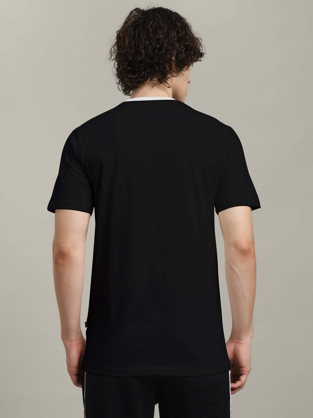 Back view of a person wearing an ANGULAR REGULAR FIT T-SHIRT BLACK, showing comfortable fit and sleek black color.