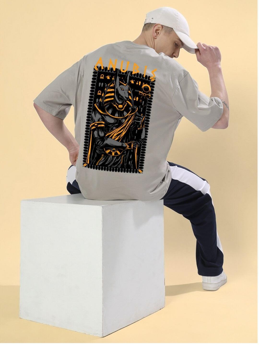 Man wearing ANUBIS EGYPTIAN PRINTED OVERSIZED T-SHIRT GREY, showcasing detailed Egyptian Anubis artwork. Unisex fashion statement.