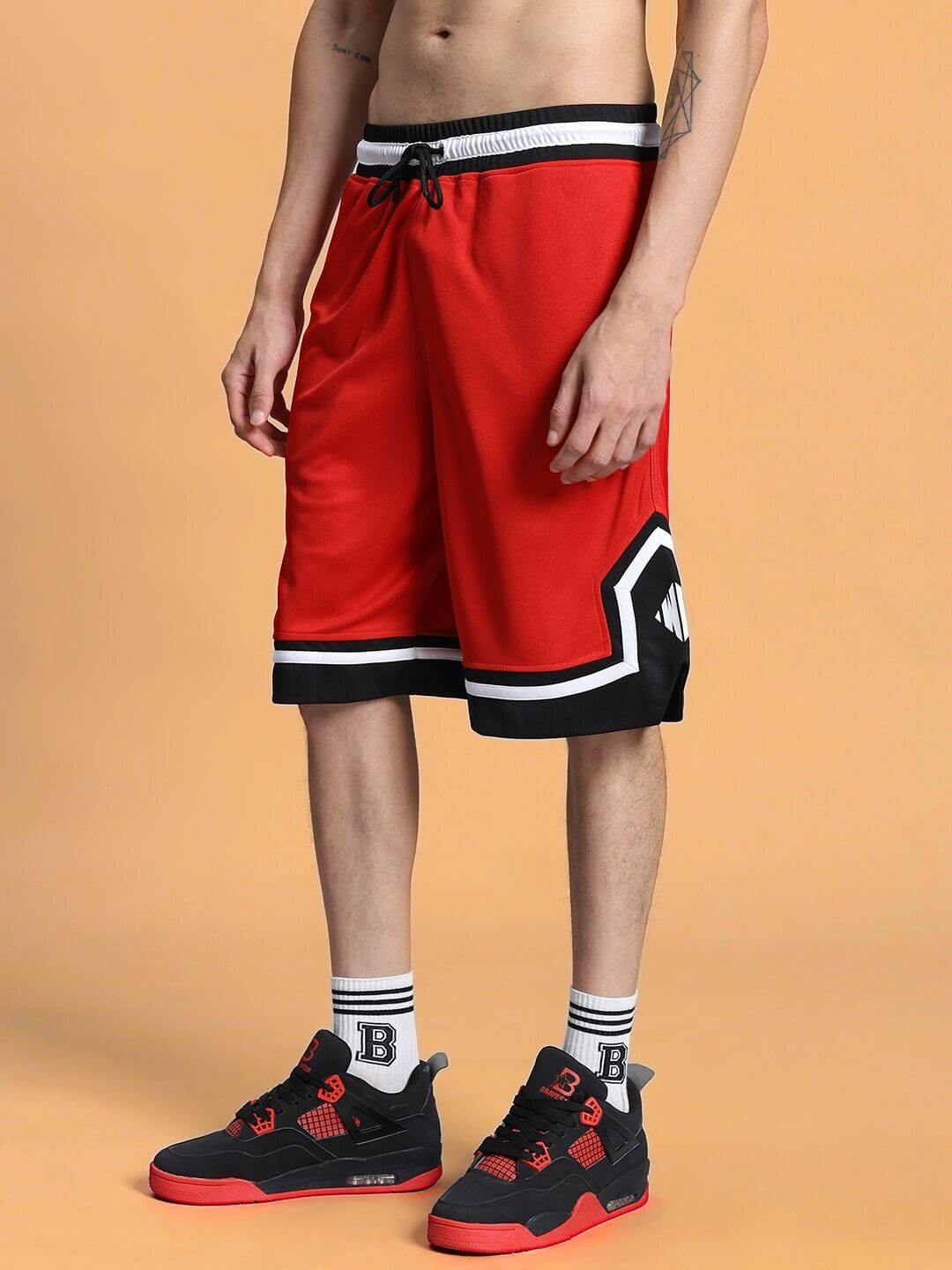 Model wearing Armado Regular Fit Red Shorts, customizable size, featuring black and white trim with sporty sneakers.