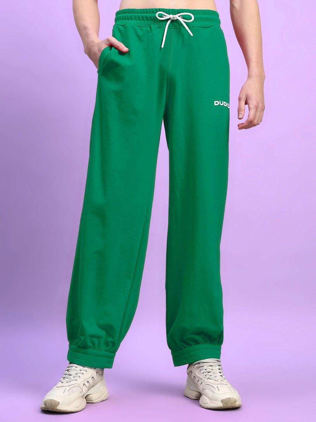 Man wearing Austrian relaxed-fit green joggers with drawstring waistband and logo, styled casually with sneakers.