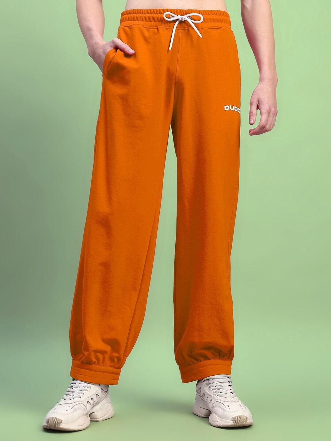 Model wearing Austrian relaxed-fit orange joggers by DUDS, showcasing drawstring waist and comfortable fit. Ideal for casual wear.