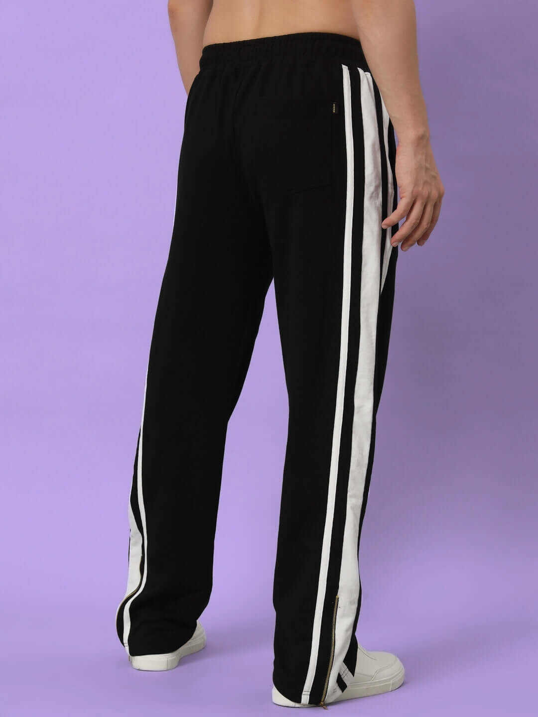 Back view of AVALON SLIT ZIPPER JOGGERS in black-white with side zipper detail, shown on a model against a purple backdrop.