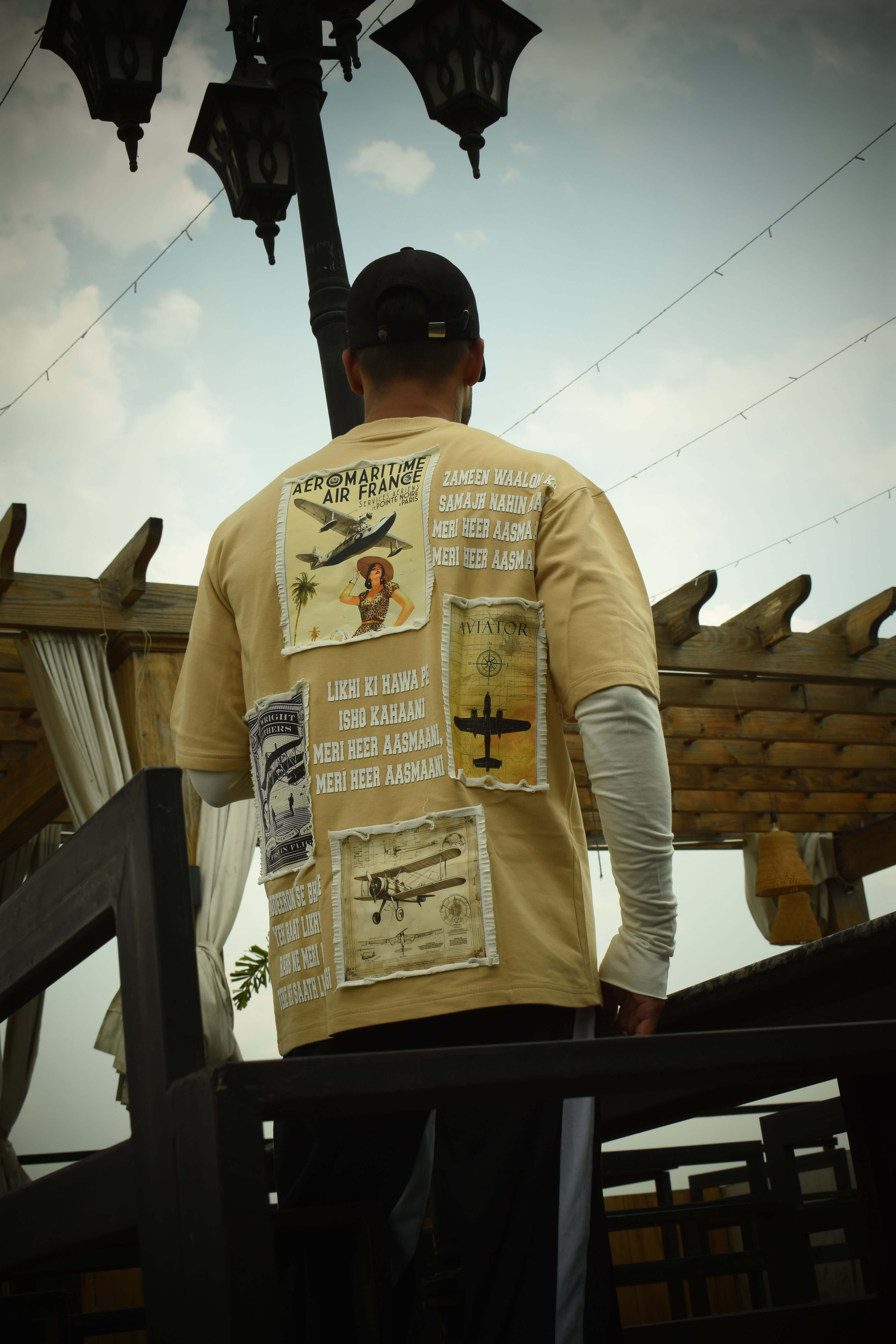 Model wearing beige aviator designer oversized t-shirt with vintage graphic design, made of premium cotton and elastane fabric.