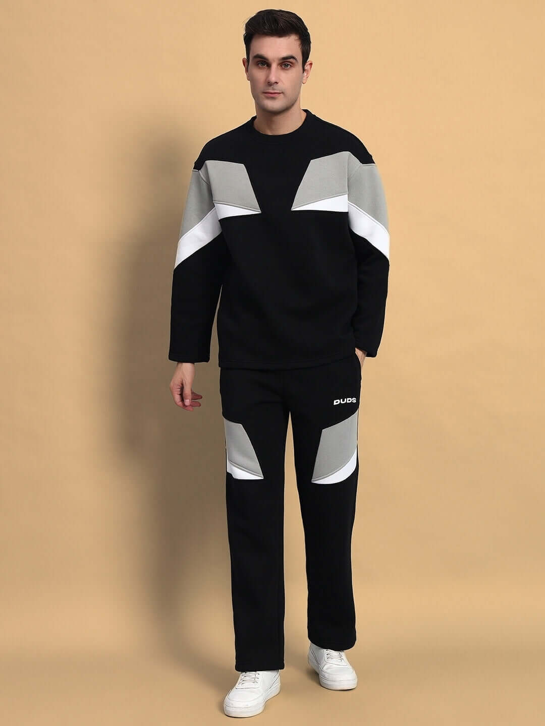 Man wearing AVIATOR Colorblock Co-Ord set in black with white and grey accents, standing against a beige background.