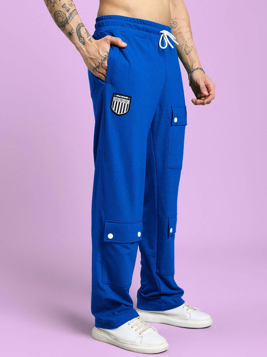 Model wearing blue flap pocket baggy jogger pants with white drawstring, showcasing casual style against a pink background.