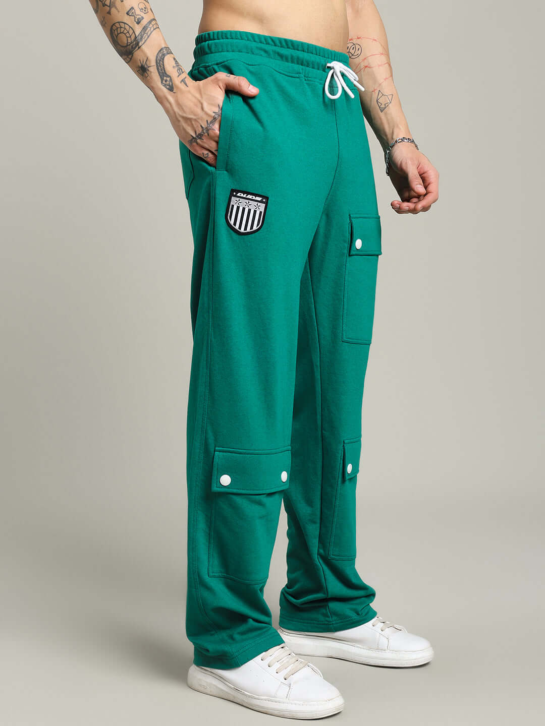 Man wearing green jogger pants with flap pockets and drawstring waistband, designed by DUDS. Made-to-order with custom sizing option.