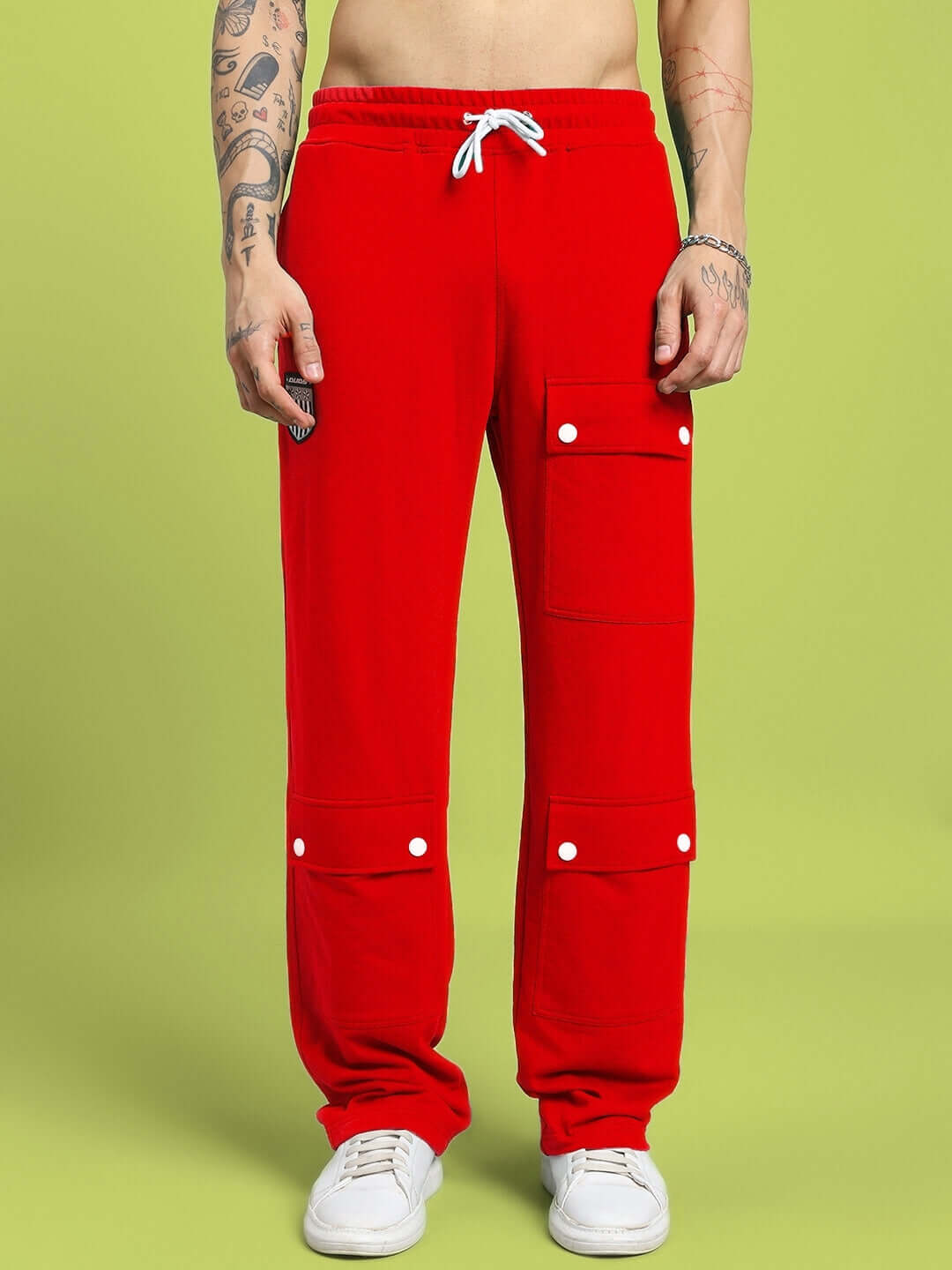 Red flap pocket baggy joggers with adjustable fit, showcased on person with white sneakers on green background.