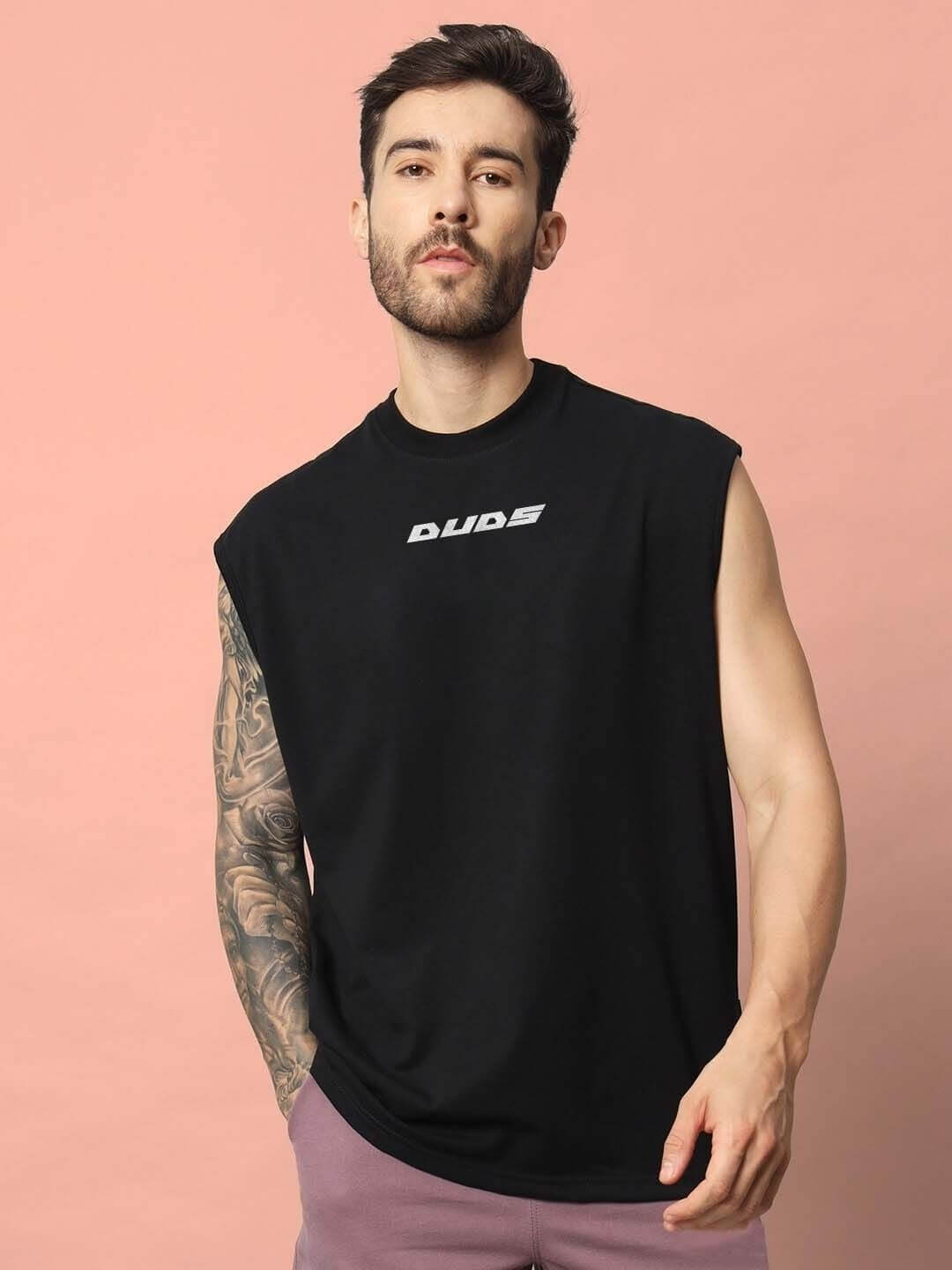 Man wearing Backbone Gym T-Shirt in black with sleeveless design against a pink background