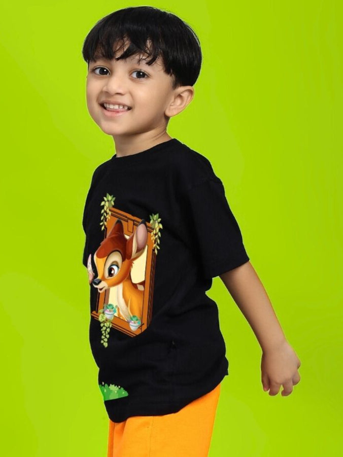 Child wearing BAMBI TOON T-SHIRT FOR BOYS AND GIRLS BLACK featuring Bambi and Thumper design, standing against a green background.