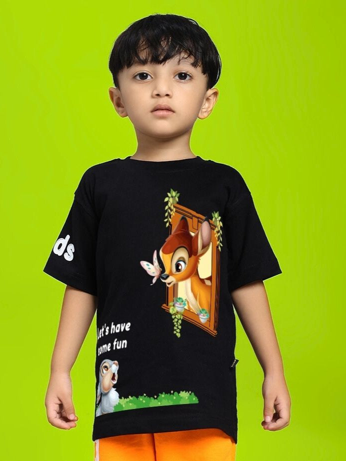 Child wearing BAMBI TOON T-SHIRT FOR BOYS AND GIRLS BLACK with Bambi and Thumper design on a bright green background.