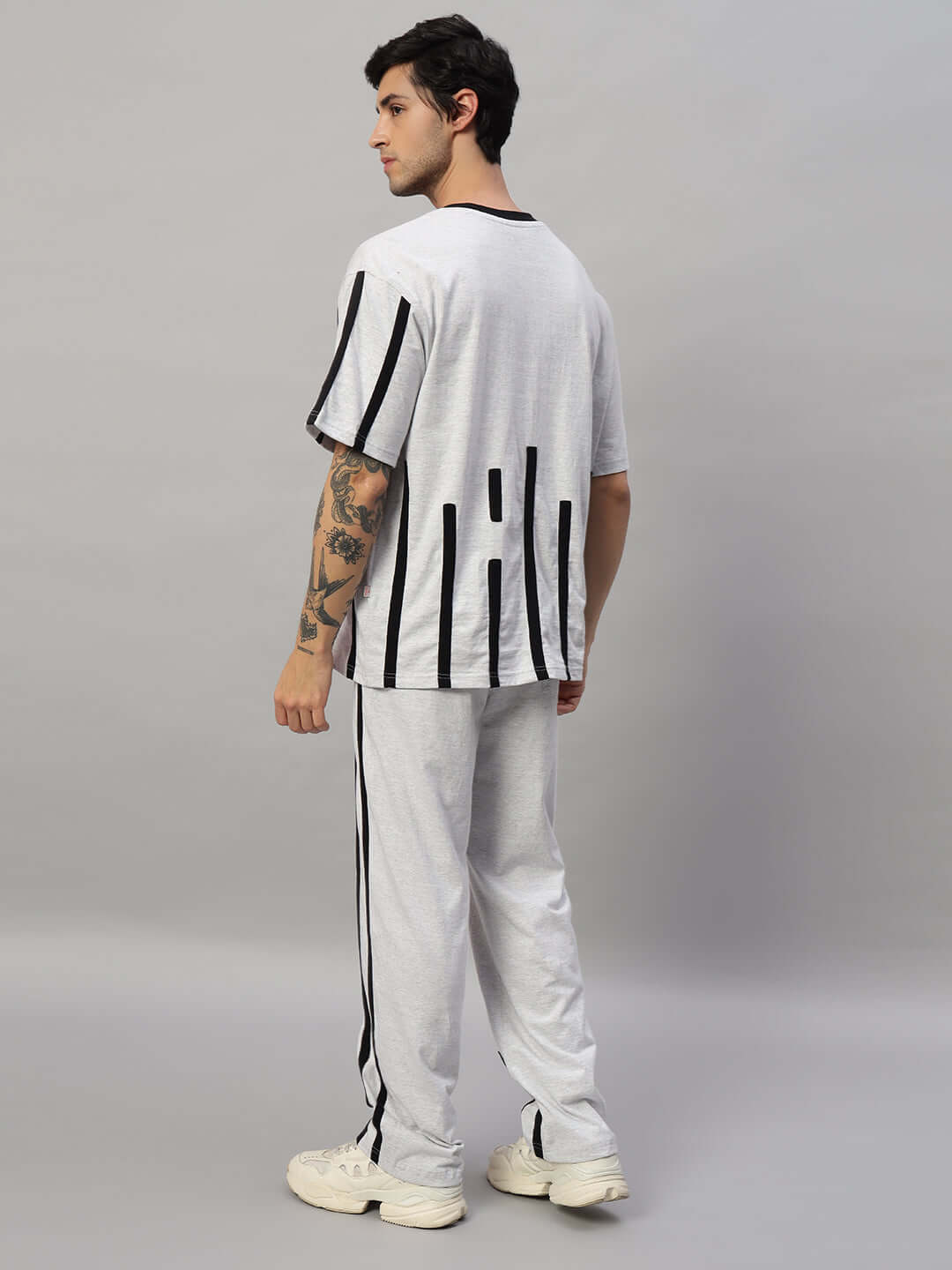 Model wearing Bastille Oversized Co-Ord Set in melange grey with black contrast panels, showcasing relaxed fit joggers and tee, back view.