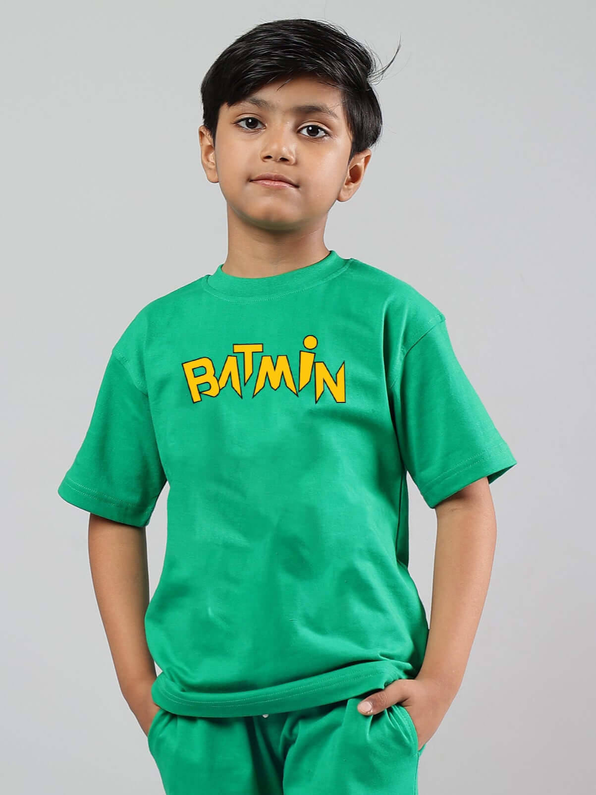 Child wearing a green Batmin t-shirt, designed for boys and girls, showcasing a bold graphic. Made from 100% cotton, 200 GSM fabric.