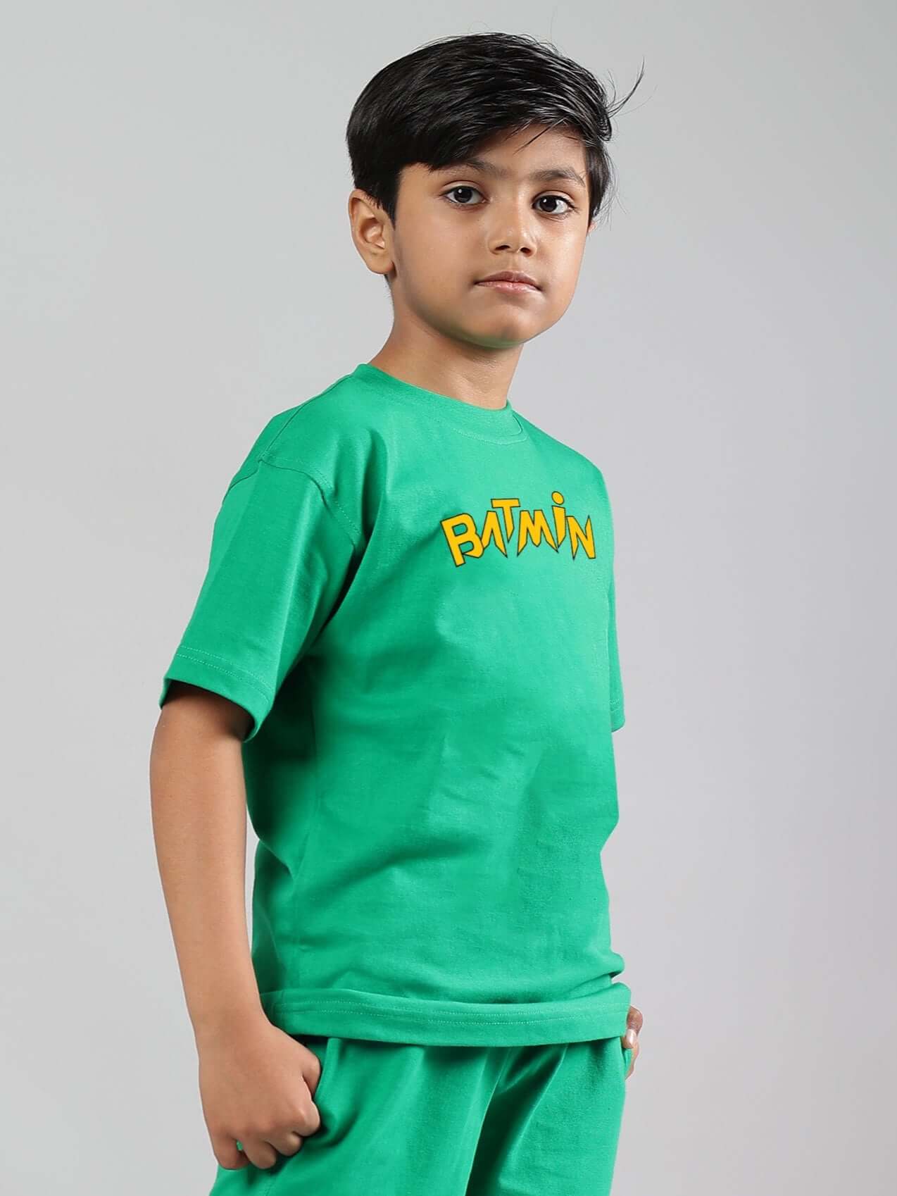 Boy wearing a green Batmin T-shirt, designed for boys and girls, made from 100% cotton for comfort and featuring a Batmin graphic.