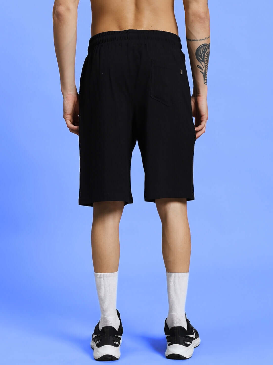 Back view of model wearing BE KIND REGULAR FIT SHORTS BLACK, showcasing the sleek design and comfortable polyester fabric.