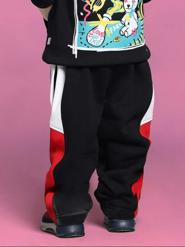 Child wearing black fleece joggers with red and white accents, suitable for boys and girls.