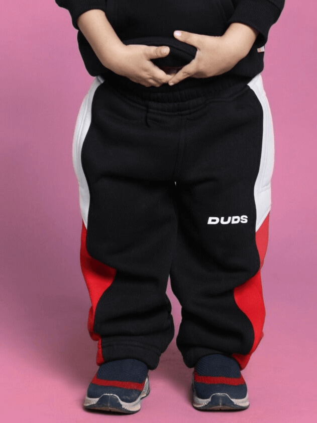 Child wearing black fleece jogger pants with red and white stripes, suitable for boys and girls. Comfortable and stylish.