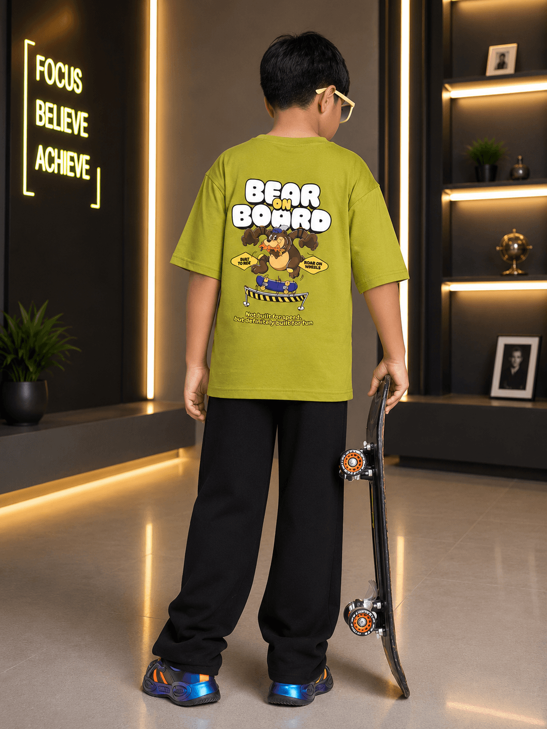 BEAR ON BOARD CO-ORD FOR BOYS GIRLS OLIVE GREEN BLACK worn by a boy holding a skateboard, showcasing a fun bear graphic.
