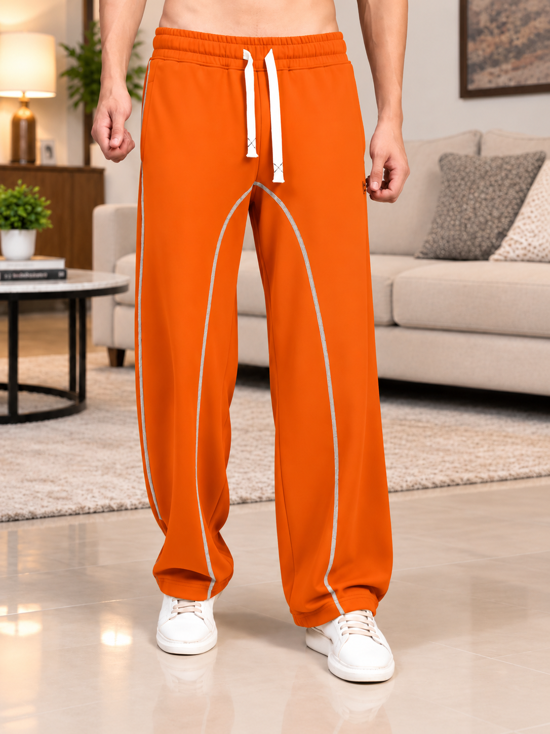 BEAT MODE FIT COTTON TERRY JOGGERS ORANGE worn by man standing in living room with white drawstring and contrast piping detail