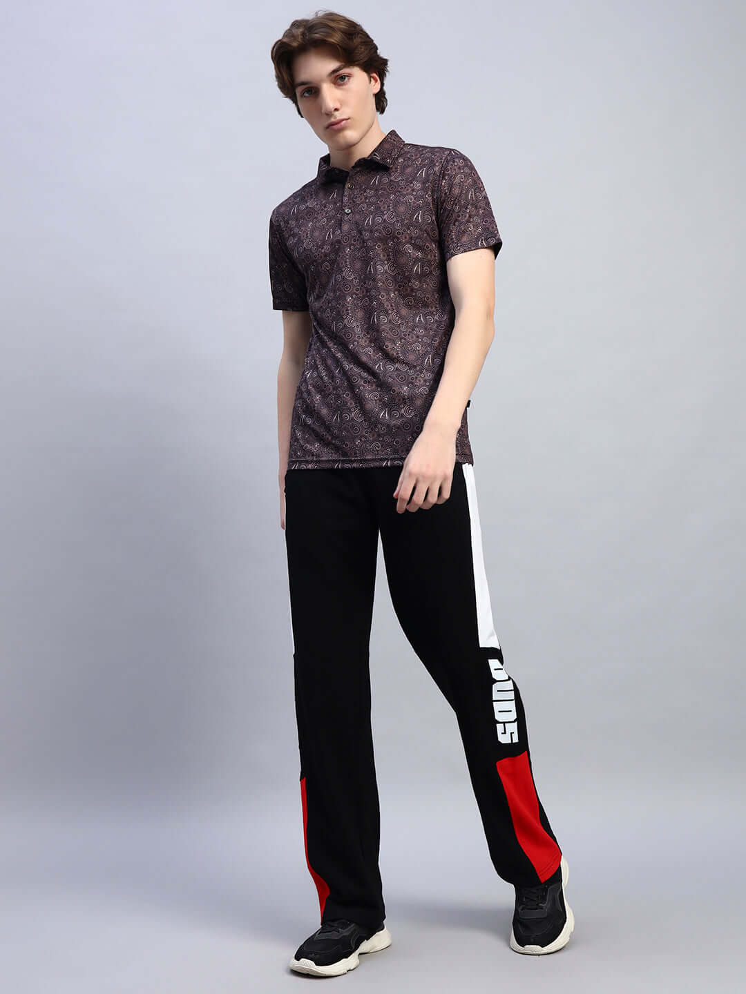 Man wearing Belgians Relaxed-Fit Joggers in black and red by DUDS, standing in a casual pose.